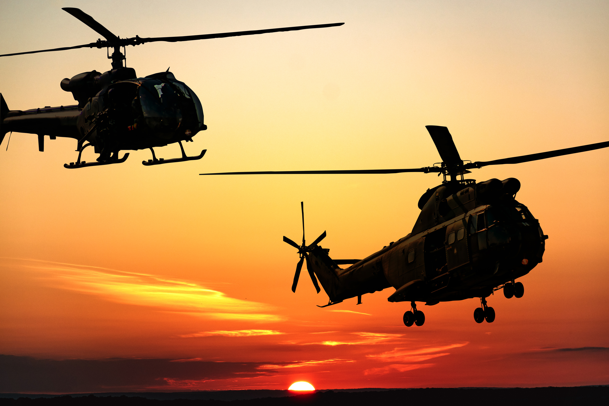Silhouette of combat helicopters at sunset in the sky, gazelle and puma side view, air transportation